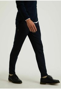 Heren donkerblauwe broek met een slim fit, een zachte textuur, subtiele zijritsen en gecombineerd met zwarte nette schoenen.