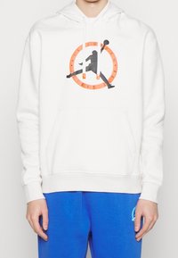 Felpa con cappuccio bianca con tasca a marsupio frontale, con una grafica circolare arancione e la silhouette nera di una persona che schiaccia una palla da basket.