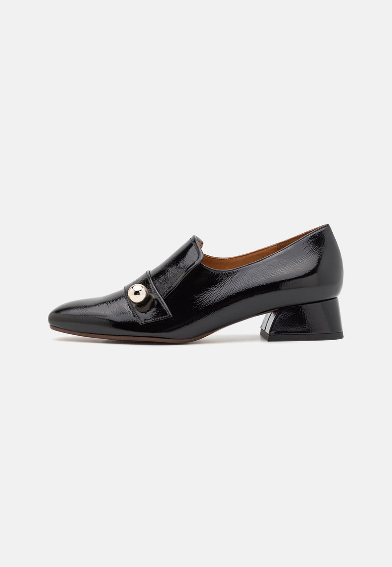 Black patent leather shoe with a rounded toe, a front strap featuring a gold accent, and a low block heel. Smooth texture and sleek design.