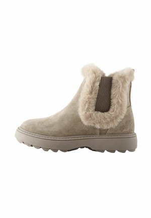 Beige enkellaars gemaakt van suède, met een zacht bontmanchet, een elastische zijband en een rubberen zool met gripgroeven.