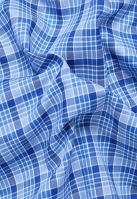 Katoenen stof met een blauw en lichtblauw geruit patroon, bestaande uit kruisende lijnen en verschillende rastergroottes, met een zachte textuur.