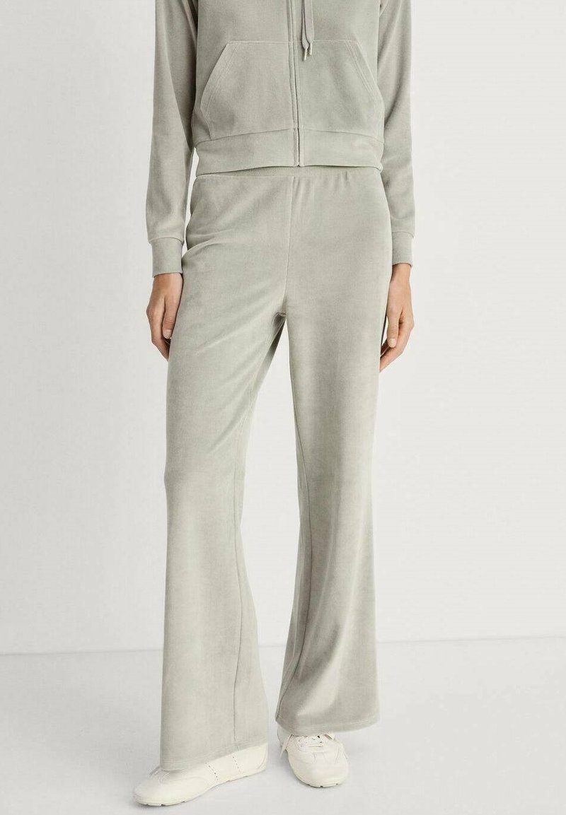 Gray velour tracksuit with a zippered, hooded jacket, and flared pants. Soft texture and relaxed fit, paired with white sneakers.