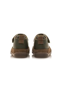 Zapatos de cuero verde y gamuza marrón con un perfil bajo, que presentan una correa de gancho y bucle, acentos texturizados y un acolchado en el collar.