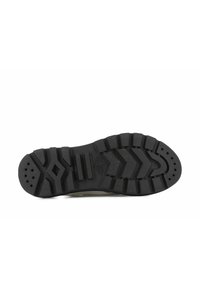 Suola di scarpa in gomma nera con battistrada testurizzato caratterizzato da solchi e motivi in rilievo per la presa, completata da fori di ventilazione circolari.