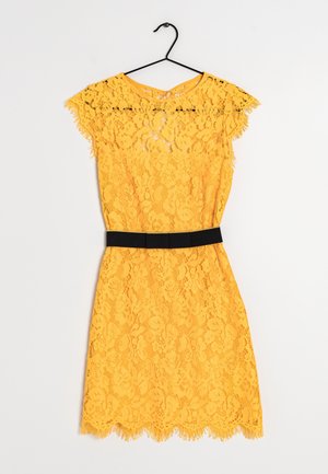 Gelbes Spitzenkleid mit kurzen Ärmeln, einem wellenförmigen Saum und einem schwarzen Taillenband als Kontrast. Der Stoff hat ein Blumenmuster.