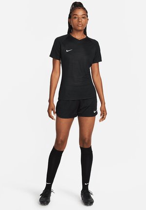 Black athletic jersey with a v-neck, short sleeves, and textured fabric. Paired with black shorts and knee-high socks, featuring a small logo.