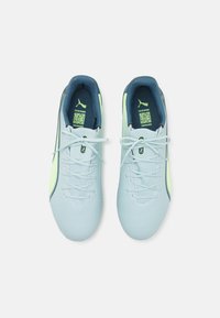 Scarpe da calcio blu chiaro con una texture liscia, dettagli verdi e un rivestimento interno blu scuro. Comprendono lacci e logo.