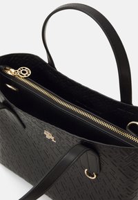 Zwarte leren handtas met een gestructureerd oppervlak, gouden ritssluiting en dubbele handgrepen. Interieur is glad met zichtbaar merklogo.