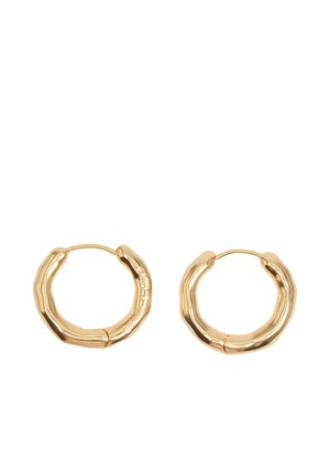 Par de pendientes de aro en tono dorado con forma irregular, acabado liso y brillante, y cierres con bisagra sobre un fondo blanco.