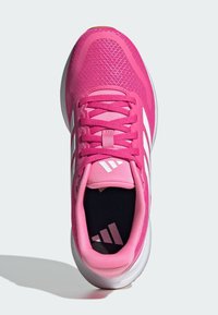 Chaussure de sport rose avec un dessus en maille, un laçage, trois rayures blanches sur le côté et une semelle souple avec un motif texturé.