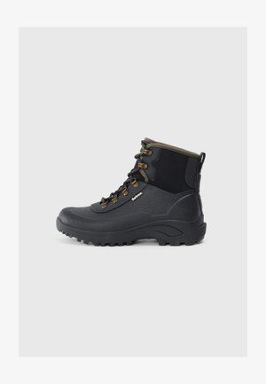 Zwarte hoogtop wandelschoen met een robuuste zool, metalen oogjes, patroonveters en een olijfkleurige afwerking, afgebeeld in profiel op een lichtgrijze achtergrond.