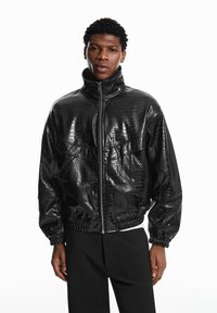 Zwarte bomberjack van nep leer met een getextureerd krokodillenpatroon, hoge kraag, ritssluiting en elastische boorden en taille.