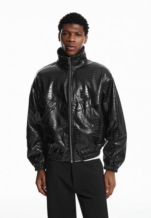 Crna bomber jakna od umjetne kože s teksturiranim uzorkom krokodilske kože, visokim ovratnikom, patentnim zatvaračem i elastičnim manžetama i strukom.