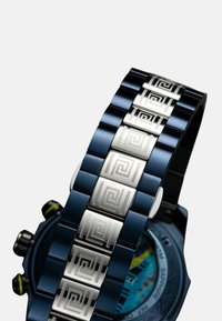 Metallarmband mit blauer Beschichtung und silbernen geometrischen Akzenten. Verfügt über strukturierte Glieder und ein integriertes Gehäuse mit farbigem Zifferblatt.
