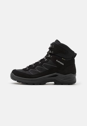 Black hiking boots with a suede and mesh upper, high ankle support, rubber sole, and metal eyelets for laces, featuring a textured finish.
