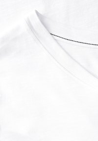 Hvid bomulds t-shirt med v-hals. Stoffet har en subtil tekstur og har en sort stikning detalje langs halsudskæringen.