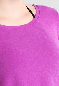 Lila kortärmad skjorta med rund halsringning, tillverkad av ett slätt tyg. Diskret textur med en lätt och luftig känsla, åtsittande vid axlarna.
