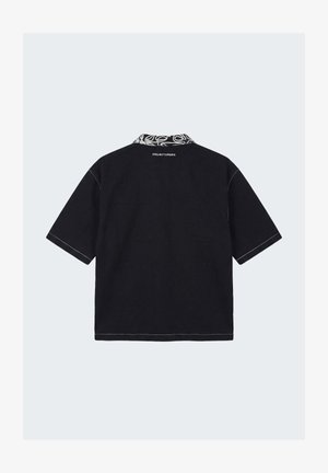 Zwart T-shirt met korte mouwen, contrasterende patroonkraag en witte tekst "PROJECTXPARIS" centraal onder de kraag op de achterkant.