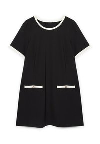 Vestido negro con mangas cortas, un escote redondo con un ribete blanco, y dos bolsillos frontales con acentos y botones blancos.