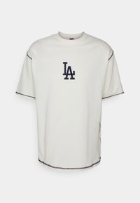 Bílý krátký rukáv tričko s černým logem "LA" umístěným na hrudi a černým kontrastním šitím na rukávech a spodním lemu.