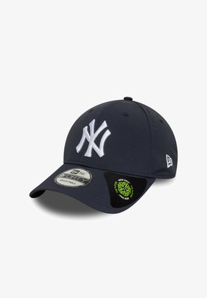 Tummansininen baseball-lippu, joka on valmistettu tekstiilimateriaalista ja jossa on valkoisella brodeerattu New York Yankees -logo sekä säädettävä hihna.