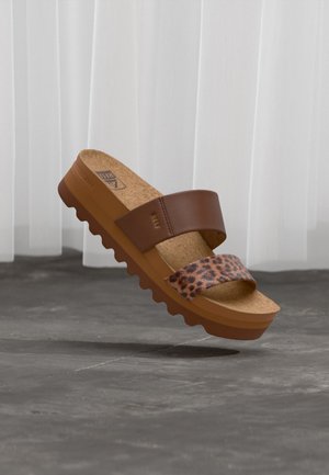 Καφέ πλατφόρμα σανδάλι με δύο λουριά, ένα μονόχρωμο καφέ και ένα με λεοπάρ σχέδιο, φελλό σε σόλα και οδοντωτή σόλα σε γκρι φόντο.