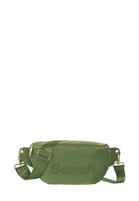 Groene stoffen heupzak met gouden rits en hardware, voorzien van een voorvak en een verstelbare schouderband. Merkennaam "Bench" in het donker gedrukt.