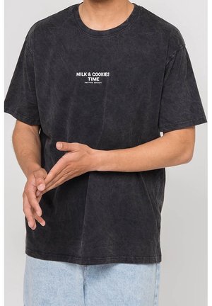 Schwarzes Baumwoll-T-Shirt mit Rundhalsausschnitt, kurzen Ärmeln und einer leicht verwaschenen Textur, auf dem "MILK & COOKIES TIME" in Weiß gedruckt ist.