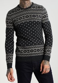 Maglione nero lavorato a maglia con accenti grigi a motivo, caratterizzato da design geometrici e motivi a fiocco di neve. Collo rotondo e vestibilità slim.