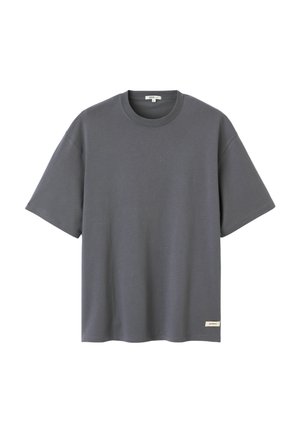 T-shirt gris foncé à manches courtes avec col rond et une petite étiquette rectangulaire près de l'ourlet inférieur sur le côté droit devant.