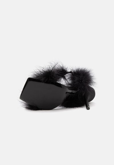 Chaussure à talon haut noire avec bordure en plumes duveteuses, allongée sur le côté montrant la semelle et le talon brillants sur un fond blanc uni.