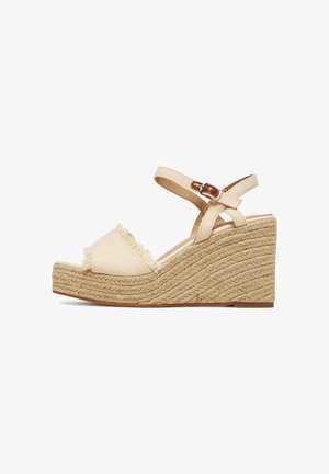 Beige wedge sandals featuring a woven rope sole and frayed fabric across the toe. Adjustable ankle strap with a metallic buckle detail.