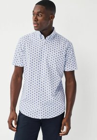 Camicetta a maniche corte, con bottoni, di colore blu chiaro con stampa di uccelli blu scuro. Presenta un colletto classico e un'orlo curvo. Materiale in misto cotone.