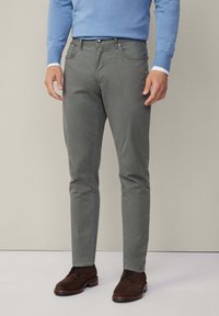 Slim-fit, lichtgrijze katoenen chinos met frontzakken en knoopsluiting, gecombineerd met een blauwe trui en bruine suède schoenen.