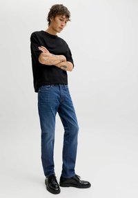 Must lühikeste varrukatega t-särk, sinised teksapüksid, läikivad mustad kingad. Lihtne disain kindlates värvitoonides ja mugava lõikega.