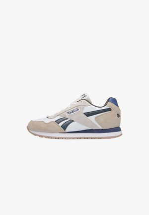 Baskets basses Reebok en suède blanc et beige avec des touches bleu marine, lacets blancs et logos de marque sur le côté et le talon.