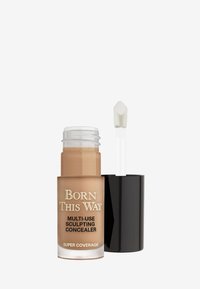 Born This Way Multi-Use Sculpting Concealer in een heldere glazen fles met een matte zwarte dop. Bevat een witte applicator met een voetje. Lichte beige tint.