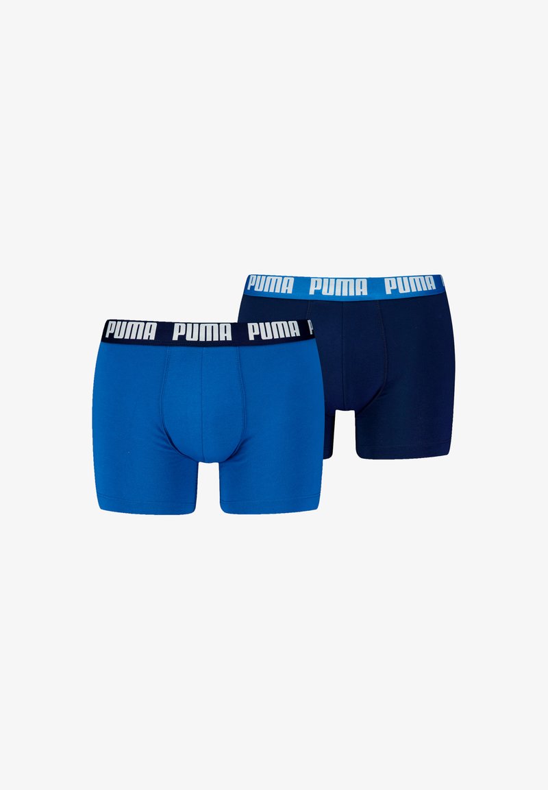 Két pár férfi boxer alsó, az egyik élénk kék, a másik sötétkék, kontrasztos elasztikus derékpánttal, amelyen fehér Puma logó található.
