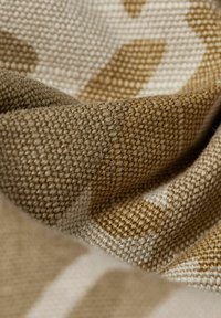 Woven fabric in beige and brown tones, featuring a textured pattern with irregular shapes and soft folds. Material appears thick and durable.