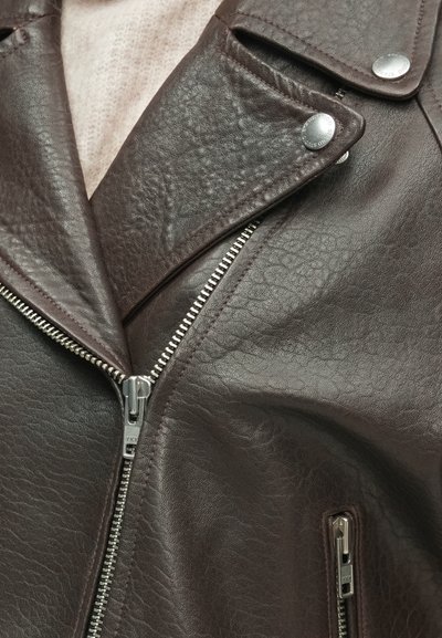 Bruine leren bikerjack met een gestructureerde afwerking, brede revers en zilveren ritssluitingen. Voorzien van twee ritszakken en drukknoopsluitingen.