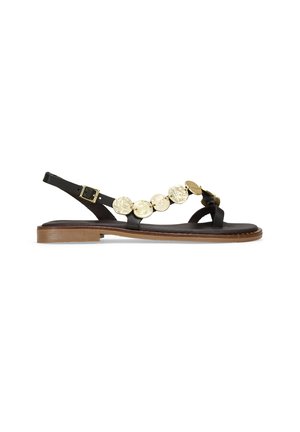 Sandal negra con correa ajustable en el tobillo, suela plana y acentos de discos metálicos en la parte superior. Material de cuero con textura suave.