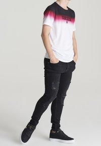 Korte mouw gradient t-shirt dat overgaat van zwart naar wit, met het 'SikSilk'-logo; gecombineerd met gescheurde zwarte skinny jeans en zwarte sneakers.