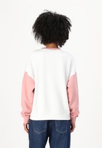 Hvit og rosa genser med lange ermer, rund hals og fargeblokkerende design. Har ribbestrikkede mansjetter og nederkant, myk tekstur.