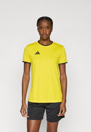 Geel sportshirt met een ronde hals, zwarte bies en een Adidas-logo op de linkerborst. Gecombineerd met zwarte shorts.