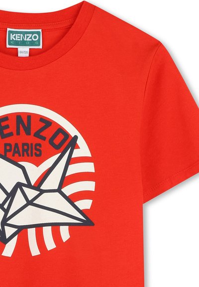 T-shirt en coton rouge avec un graphique central représentant une grue en origami blanc et noir, orné d'un logo circulaire "KENZO PARIS" et de motifs de vagues. Manches courtes.