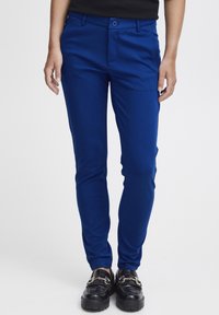 Helle blaue, taillierte Hose mit glatter Textur, mit Knopfverschluss und vorderen Taschen, getragen mit schwarzen Mokassins.