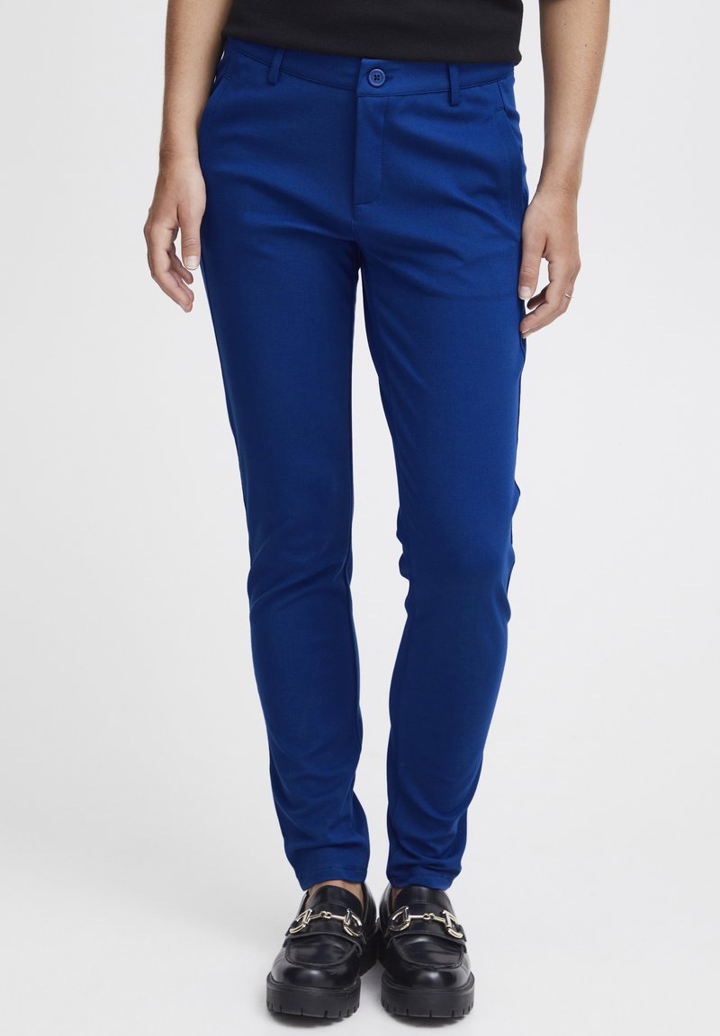 Helle blaue, taillierte Hose mit glatter Textur, mit Knopfverschluss und vorderen Taschen, getragen mit schwarzen Mokassins.
