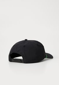 Gorra negra con visera curvada, hecha de tela liviana. Presenta un acento verde, correa ajustable en la parte posterior y detalles cosidos.