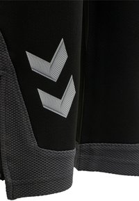 Svart atletisk plagg med texturerade grå accenter och en logo med två vitfärgade chevronformer, som betonar sportiga designelement.