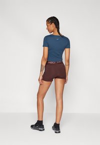 Marineblå t-skjorte med korte ermer og Nike-logo, parret med brune treningsshorts med merket livvidde. Svarte joggesko.